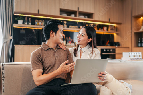 Young adult couple financial partners discussing future real estate investment plans together using laptop computer modern home living room apartment