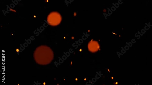 Glowing orange embers floating against a dark black background
