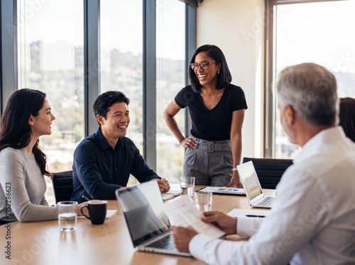 Foto Cheerful diverse business team collaborating in a bright modern office meeting, discussing ideas and laughing together