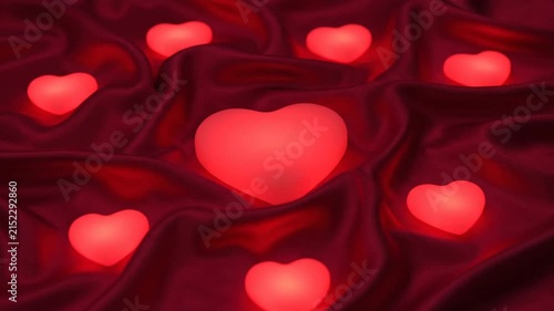 Glowing red hearts resting on a soft dark fabric background