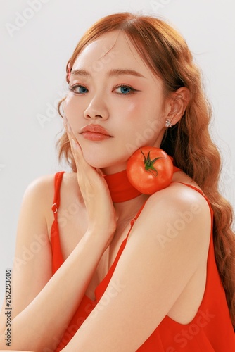 Asian Woman Touching Cheek with Tomato for Antioxidant Skincare Concept