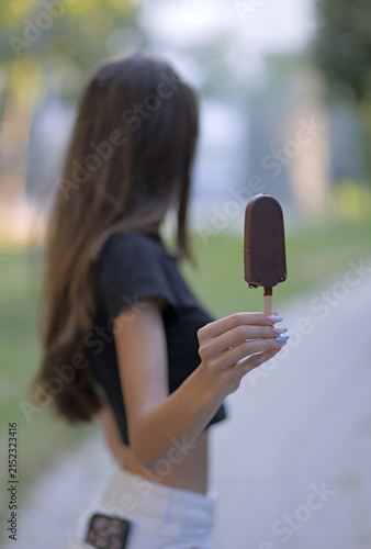 Young woman holding chocolate ice cream bar outdoors