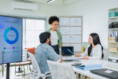 Three colleagues of different backgrounds gather closely around a tablet, engaged in a focused discussion of business data a genuine portrait of diverse teamwork and inclusive workplace collaboration