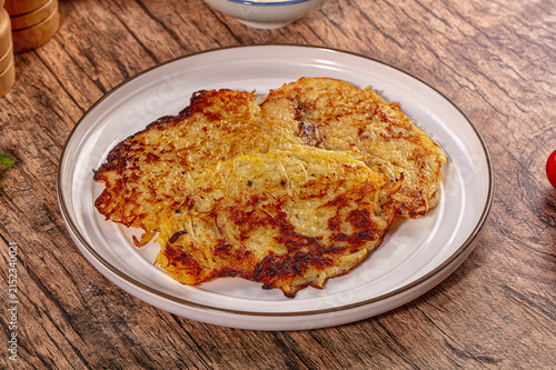 Canvastavla Crispy golden hash brown pancakes on white plate over rustic wood table