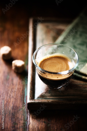 Coffee in glass cup on a dark wooden background. Soft focus. Close up. Copy space.