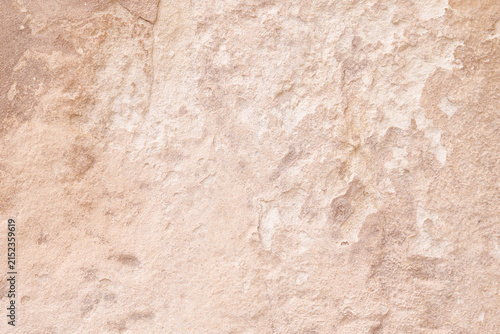 Abstract texture of an ancient weathered stone wall with beige plaster cracks