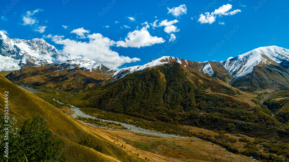 Naklejka premium Landscape photograph of snow covered mountains and glacier river valley viewed from Chkhutnieri pass in Svaneti Georgia.