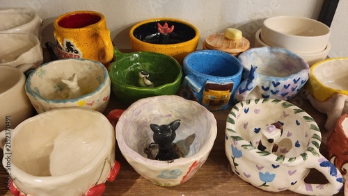Colorful handmade ceramic bowls and cups displayed in pottery workshop