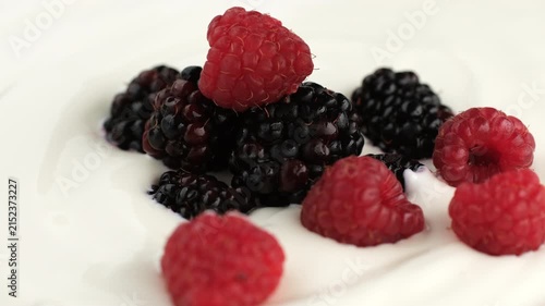 Fresh berries falling down on white greek yogurt, close up. Creamy dessert texture, fresh healthy breakfast