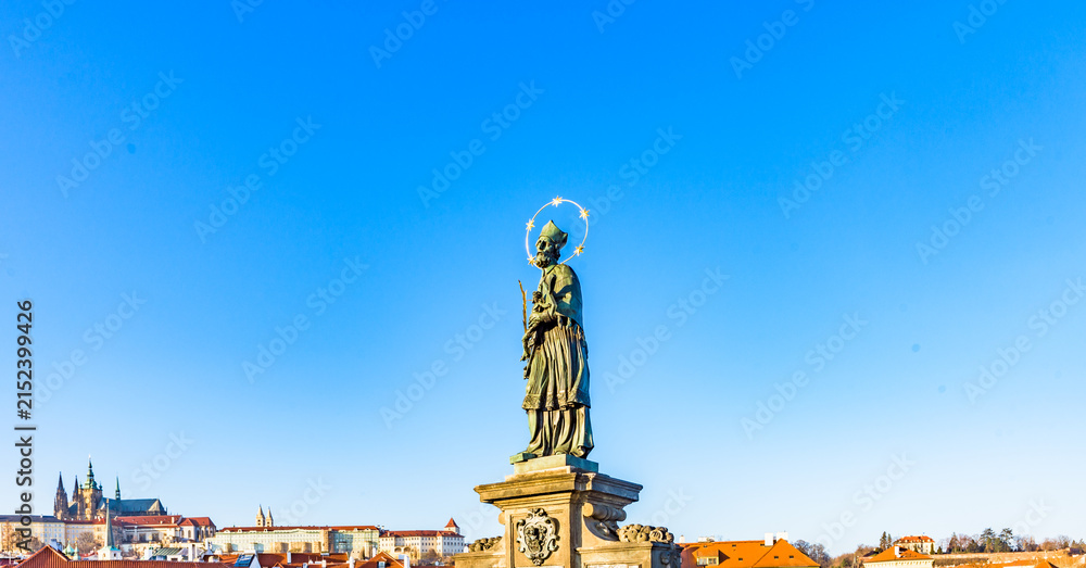 Fototapeta premium Statue of St John of Nepomuk on Charles Bridge in Prague, Czechia, UNESCO World Heritage Site, against clear blue sky