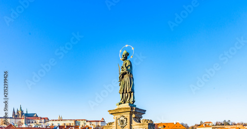 Statue of St John of Nepomuk on Charles Bridge in Prague, Czechia, UNESCO World Heritage Site, against clear blue sky