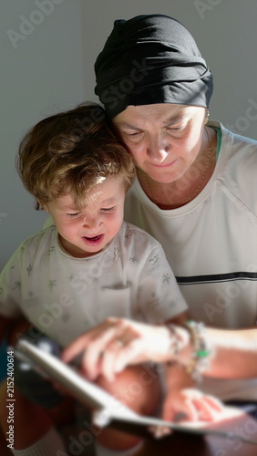 Konstfotografi Mother recovering from cancer reading storybook to toddler on sofa, celebrating
