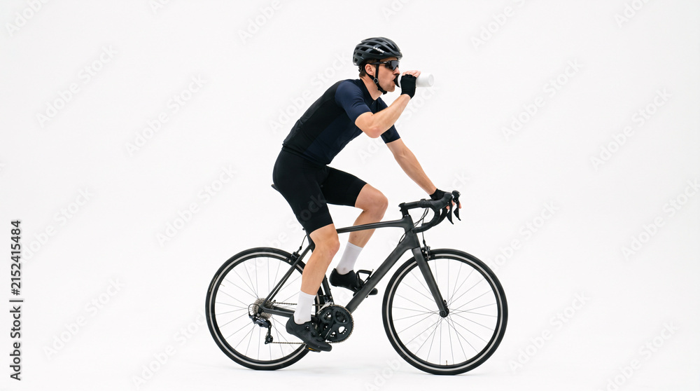 Fototapeta premium Male cyclist in full cycling gear on a road bike, taking a drink from a water bottle against a clean white background.
