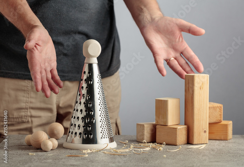 Quadro su tela Man grating wooden blocks into round shapes, illustrating pointless work, wasted effort and an inefficient process