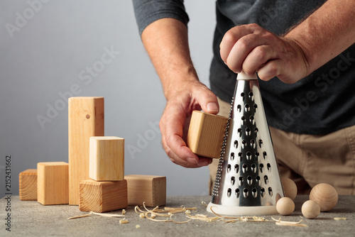 Obraz na płótnie Man grating wooden blocks into round shapes, illustrating pointless work, wasted effort and an inefficient process