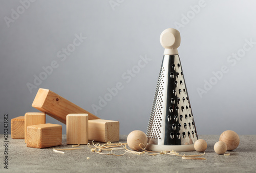 Cuadro en lienzo Wooden blocks and finished wooden balls beside a kitchen grater, illustrating pointless work and wasted effort