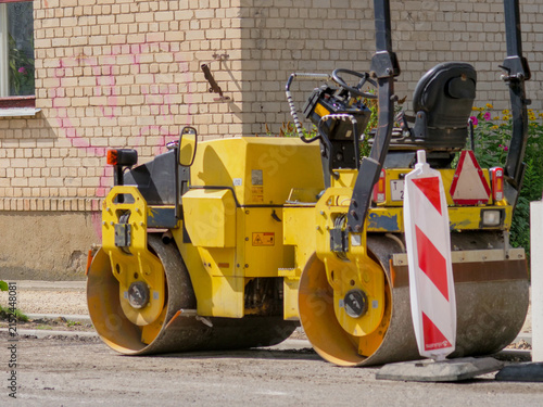 Konstfotografi Yellow Tandem Vibratory Road Roller and Safety Warning Sign at an Urban Street C