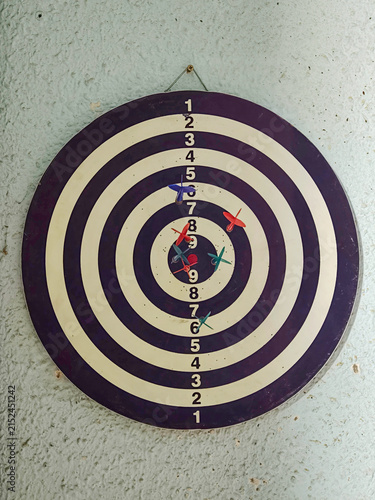 Dartboard with darts hitting target and missing