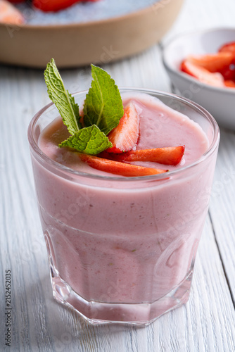 Glasses of strawberry smoothie on white wooden background