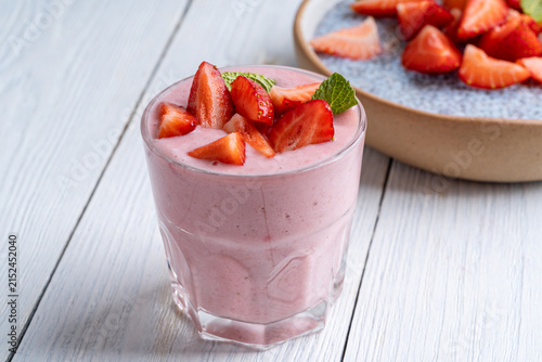 Glasses of strawberry smoothie on white wooden background