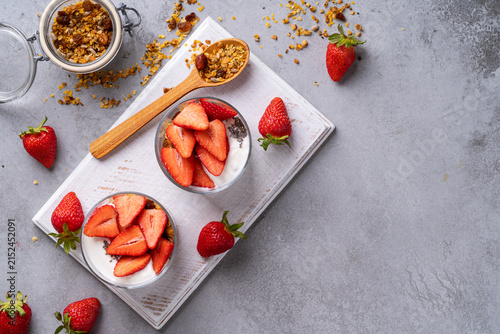 Homemade gluten free granola with yoghurt, chia seeds, and fresh strawberries in glasses, healthy breakfast