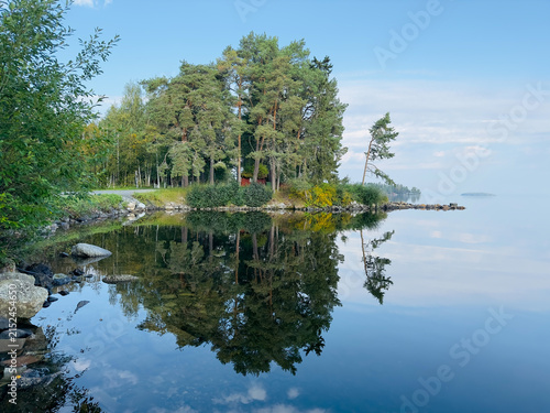Tranquil Swedish lake reflecting trees and sky on a clear day