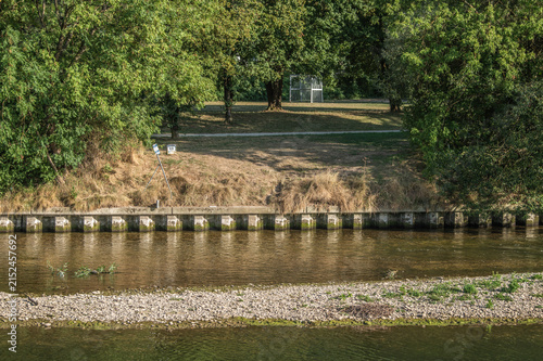 Hitzeschaden verdorrtes Gras an Uferböschung und Kiesbank  wegen Niedrigwasser am Ermszufluss in den Fluss Neckar in Neckartenzlingen