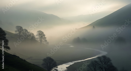 Misty valley with winding river during soft sunrise light over rolling hills and bare trees