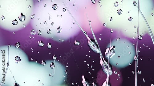 Gravity pulling cluster of water droplets, merging into vertical streaks on glass, bokeh