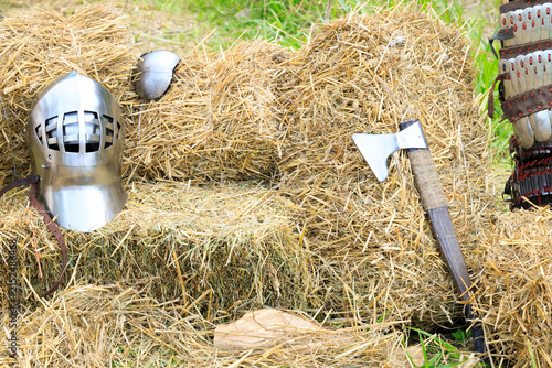 Fotografía Medieval knight's steel helmet and axe resting on hay bales