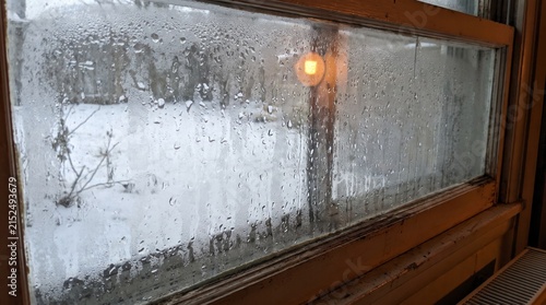 Condensation forming on a single-pane basement window in winter