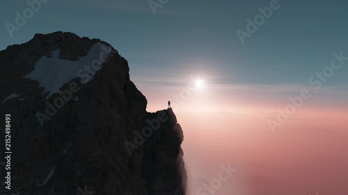 Majestic Mountain Peak at Sunrise with a Lone Figure Amidst Ethereal Clouds