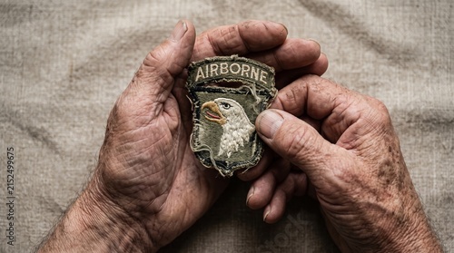 Close up of aged hands holding an Airborne patch. Concept: Memorial Day, military honor, veteran tribute, history, and remembrance for editorial and commercial use. Generative AI.