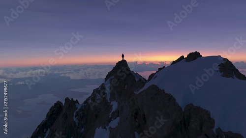 Solitary Figure Standing on a Majestic Mountain Peak at Sunrise or Sunset