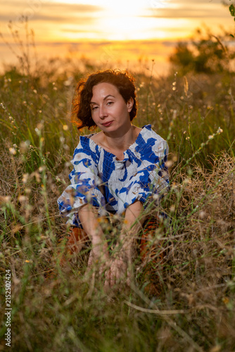 Woman Sitting in Meadow at Sunset