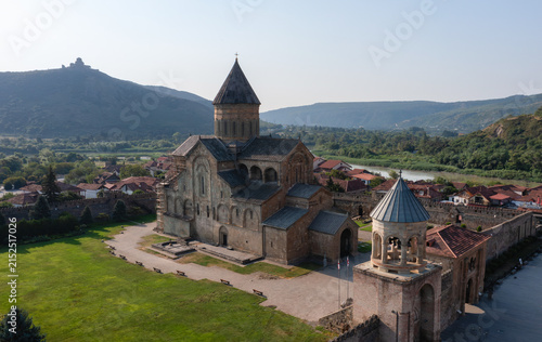 Historic Orthodox cathedral surrounded by green hills and traditional houses in Georgia