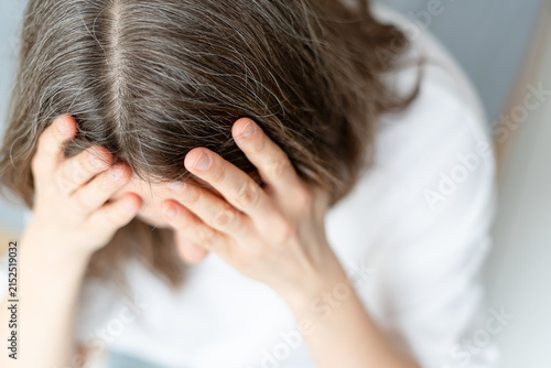 Close up of a woman dealing with both hair thinning and premature graying at once. The mature adult faces distressing combination of hair problems together. Mother feels hopeless about her locks.