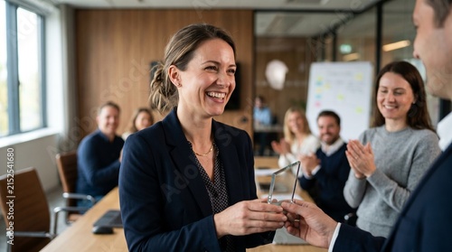 A professional receiving a small, symbolic recognition trophy during an informal team meeting; a spontaneous smile and genuine emotion, with colleagues quietly applauding in the background.