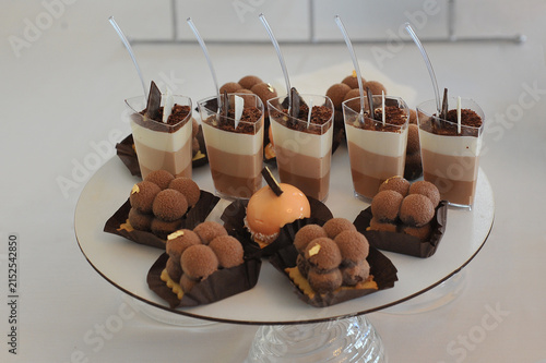 Konstfotografi An assortment of chocolate desserts served in small cups and trays including layered mousse shots  , chocolate truffles and a glossy orange mousse