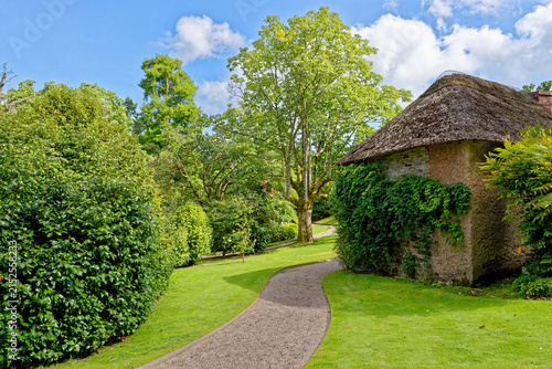 Traditional Thatched Cottage and Winding Gravel Path on Estate Grounds