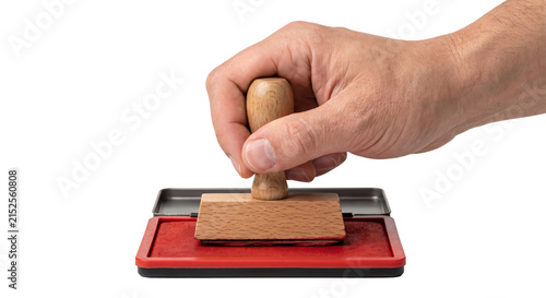 Fotografie Hand holding a wooden stamp over a red ink pad for official approval