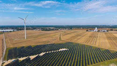 Aerial drone view of wind turbine and solar panel farm surrounded by agricultural fields – renewable energy landscape photo