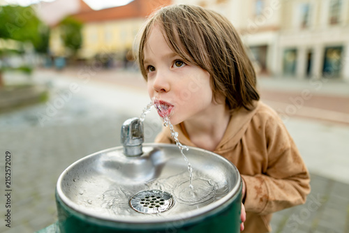Konstfotografi Playful young boy having fun with a public drinking fountain in the city