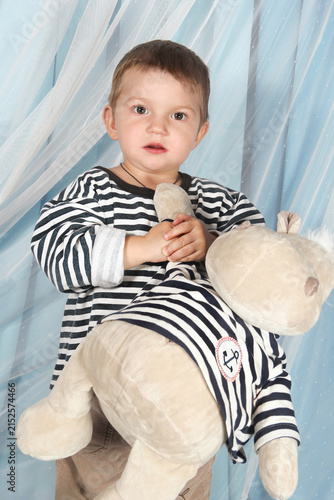 Small boy with a stuffed animal in his hands on a blue background