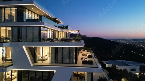 Modern Luxury Architecture: White Geometric Building with Illuminated Glass Balconies at Dusk, Ideal for Real Estate Marketing.