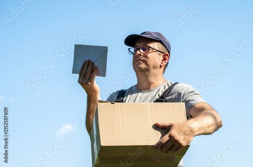 Фотография A mail carrier stands outside under a blue sky
