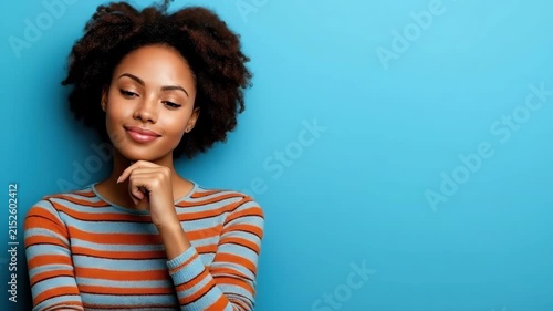 Thoughtful african woman in striped sweater posing against blue background