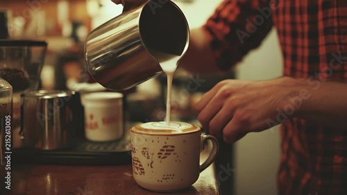 Young caucasian man preparing cappuccino in coffee shop with latte art