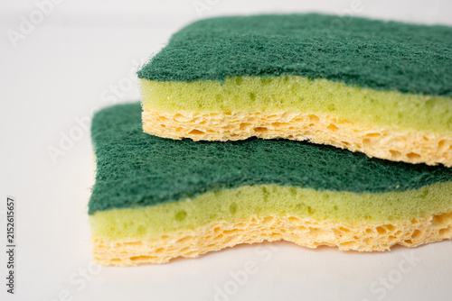 Two green and yellow kitchen sponges on white background.