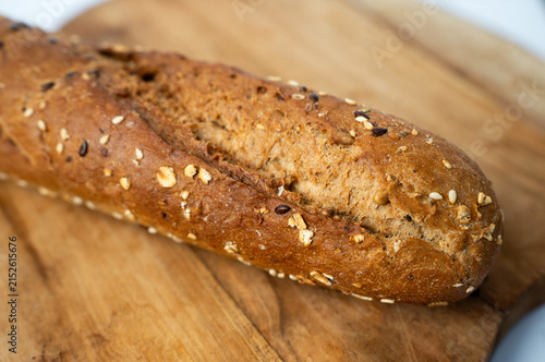 Whole grain baguette on a wooden cutting board.